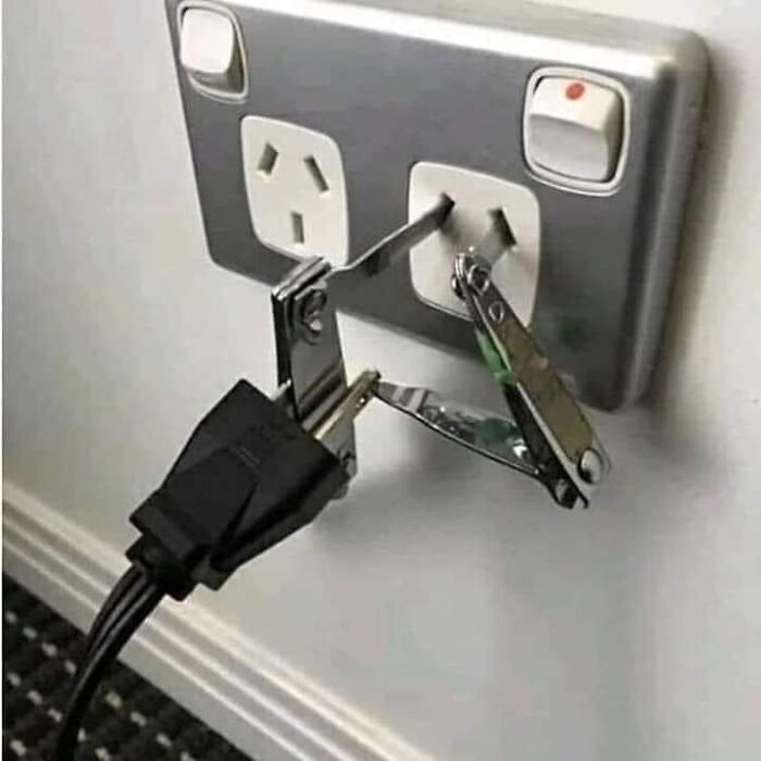 Unsafe outlet hack: plug secured with multitool, defying OSHA safety regulations.