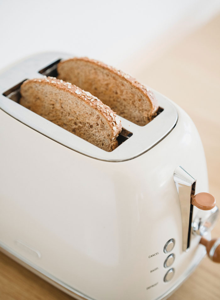 Close-up of a white toaster with two slices of whole grain bread, highlighting everyday kitchen curiosities and facts.