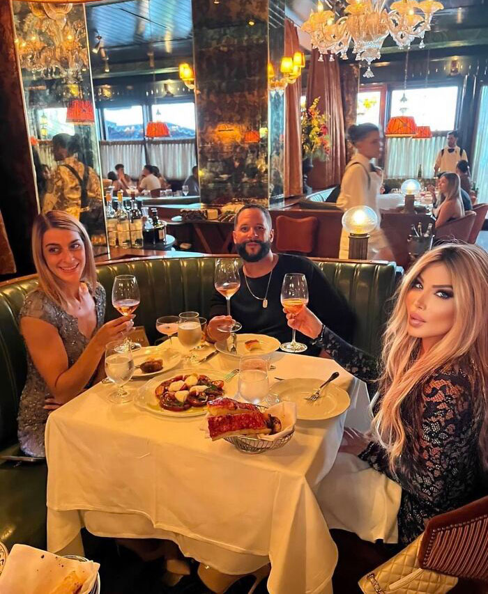 Three people posing with wine glasses in a fancy restaurant, illustrating Instagram reality with staged photos.