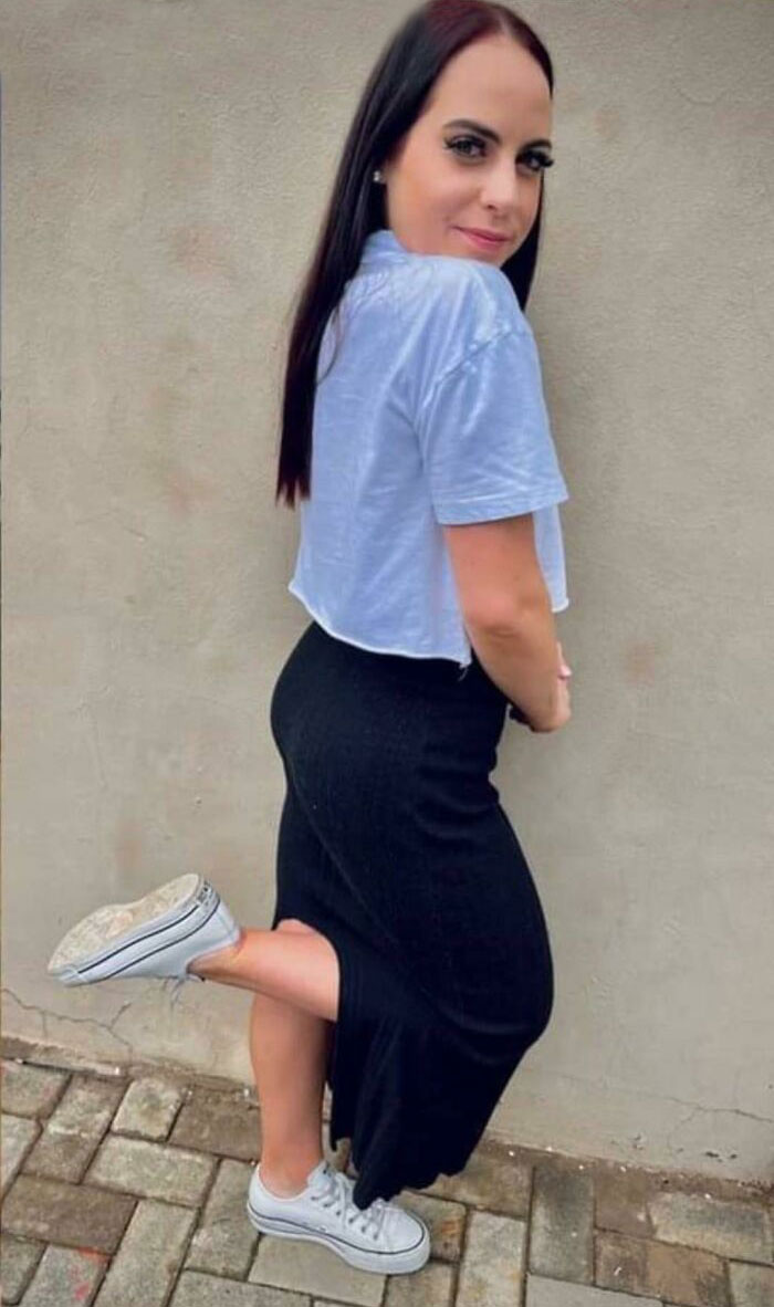 Woman posing in casual outfit by a plain wall, illustrating Instagram reality and fake pics online.