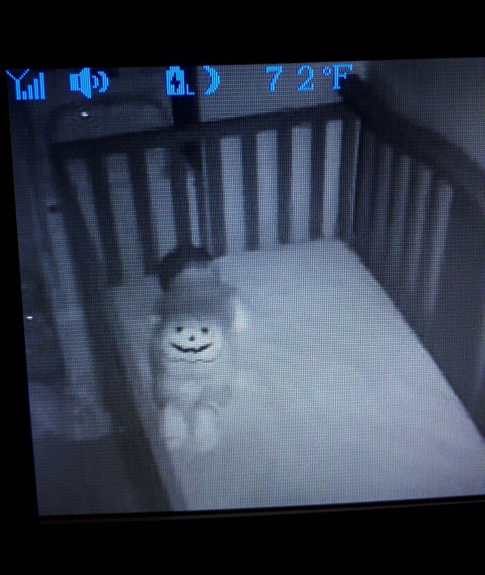 Night vision baby monitor showing a child in a crib with a Halloween pumpkin face filter, capturing kids making parents laugh.