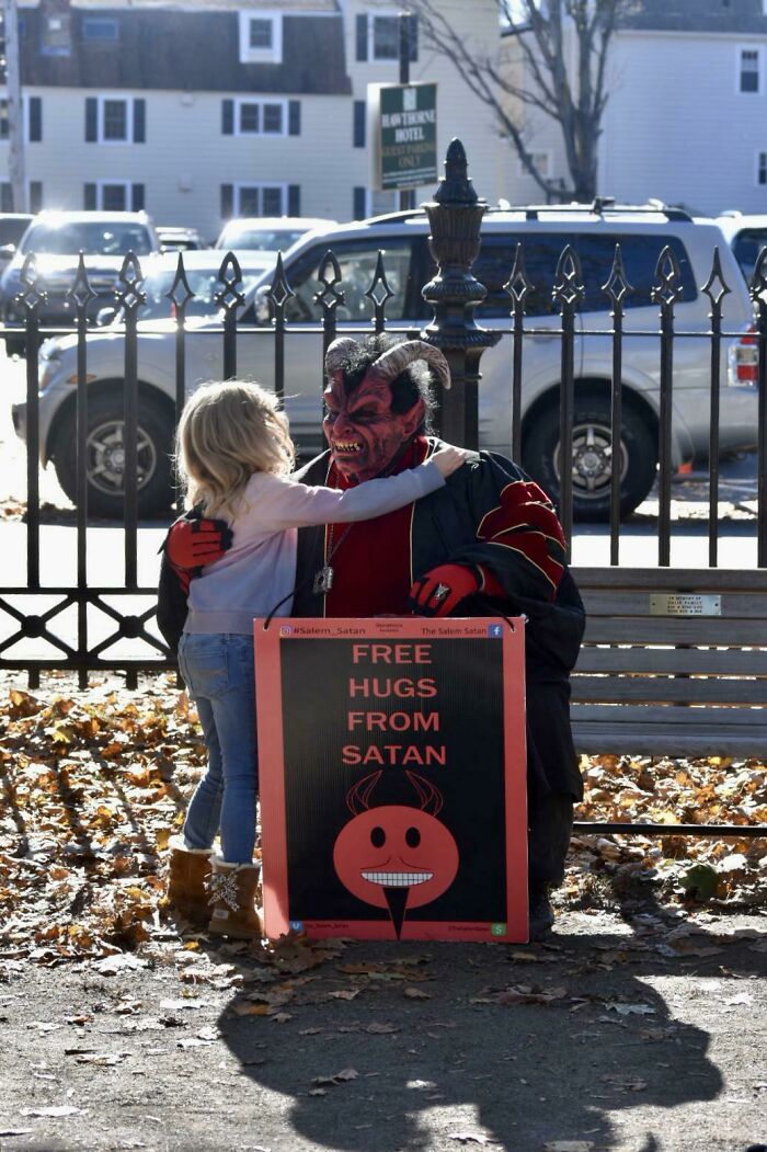 Child hugging person dressed as Satan holding free hugs sign, funny Halloween moment kids made parents laugh hard.