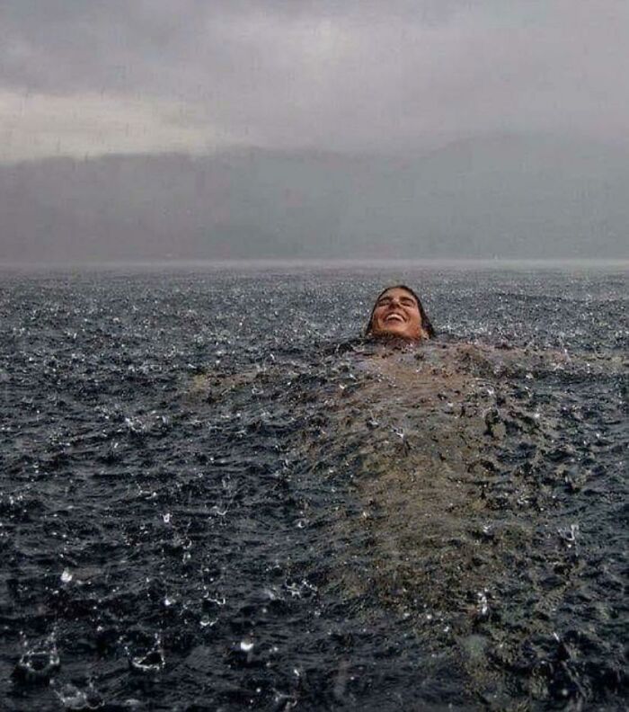 Person floating in dark ocean water during heavy rainstorm, evoking fear of the ocean and dangerous conditions.