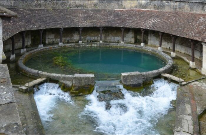 Ancient circular stone water basin with rushing flowing water, evoking frightening ocean-like vibes.