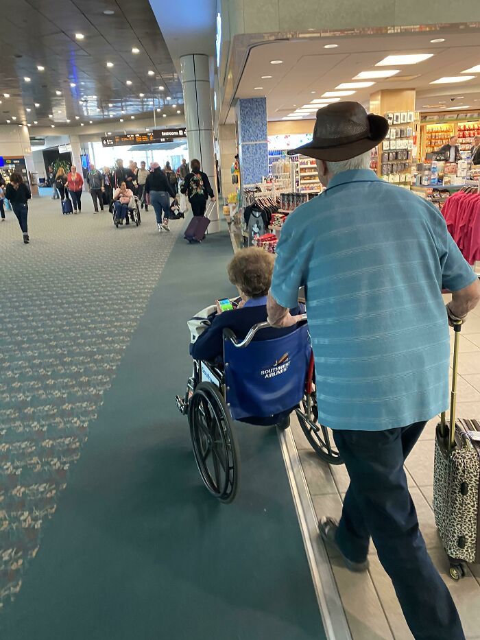 This Little Lady Has Been Asking Her Husband To Push Her Around So She Can Catch Pokémon While They Wait To Board Their Flight