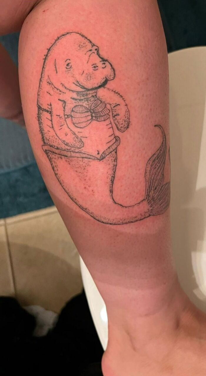 Illustration of a tattoo featuring a mermaid with a manatee head on someone's leg.