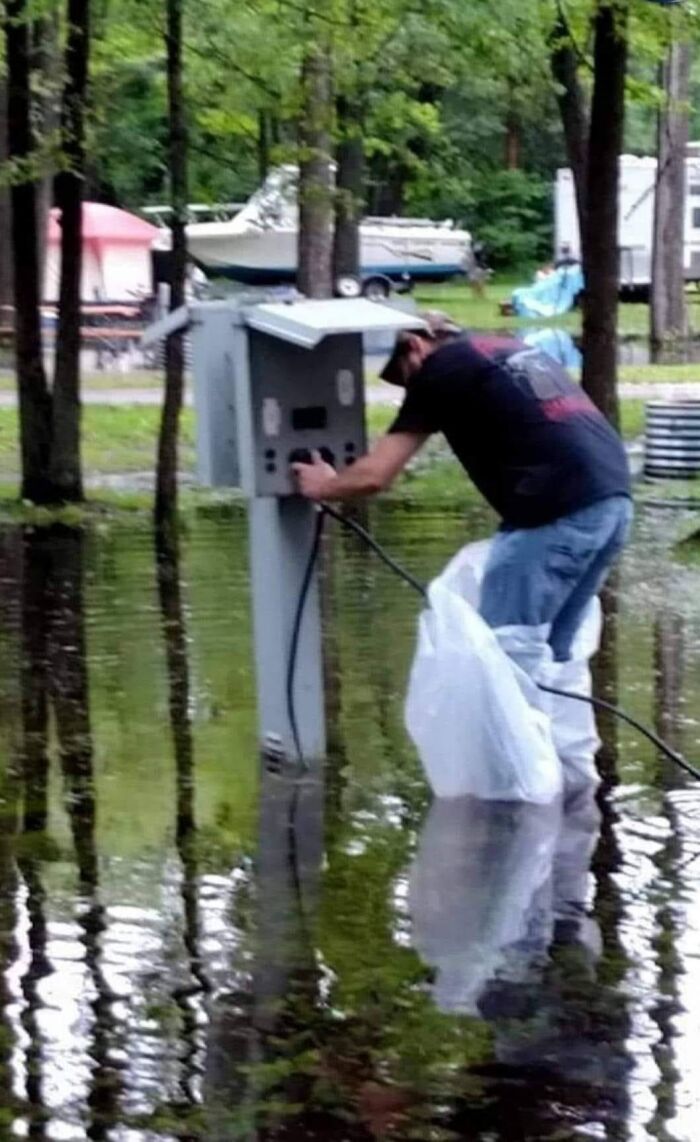 Man ignoring OSHA safety, working with electrical panel in flooded area.