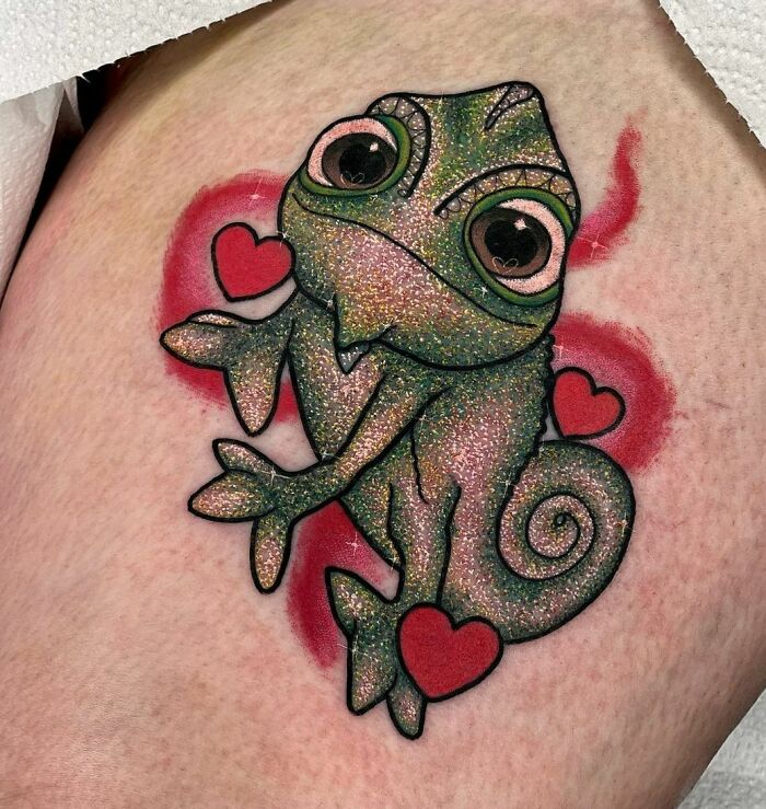 Glitter tattoo of a cute chameleon with hearts, featuring a shimmering design on skin.