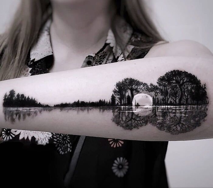 Creative tattoo design of a serene landscape with a moonlit reflection on a person's arm.