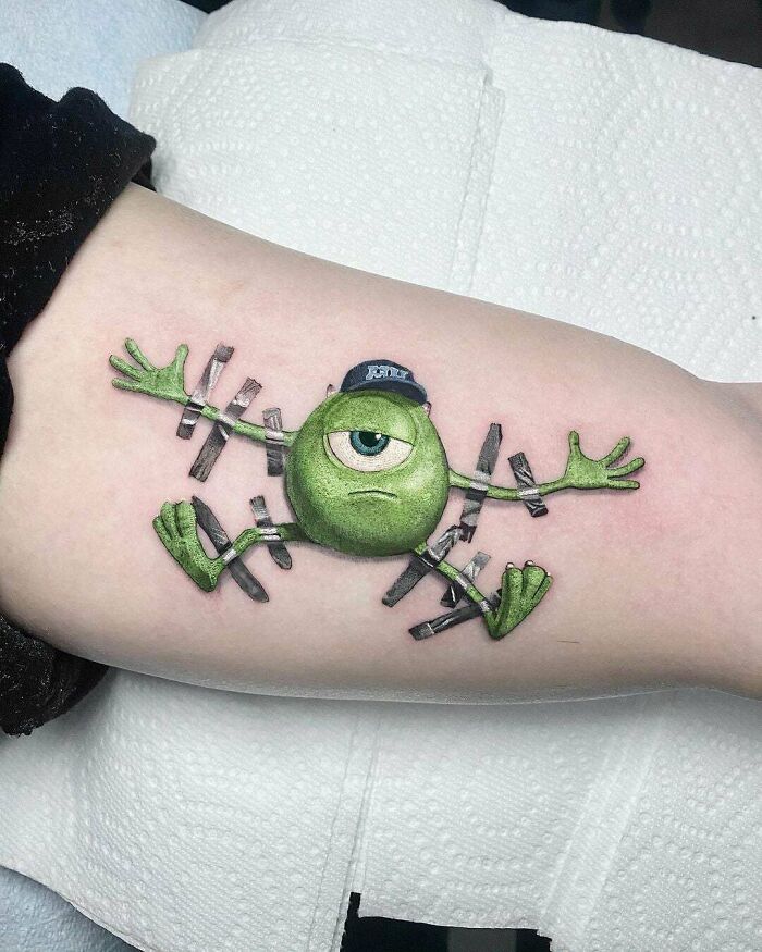 Creative tattoo design of a green cartoon character with flexible limbs.