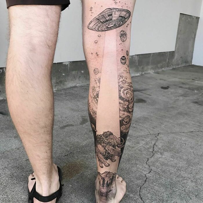 Creative tattoo design featuring UFO and space-themed elements on a person's leg.