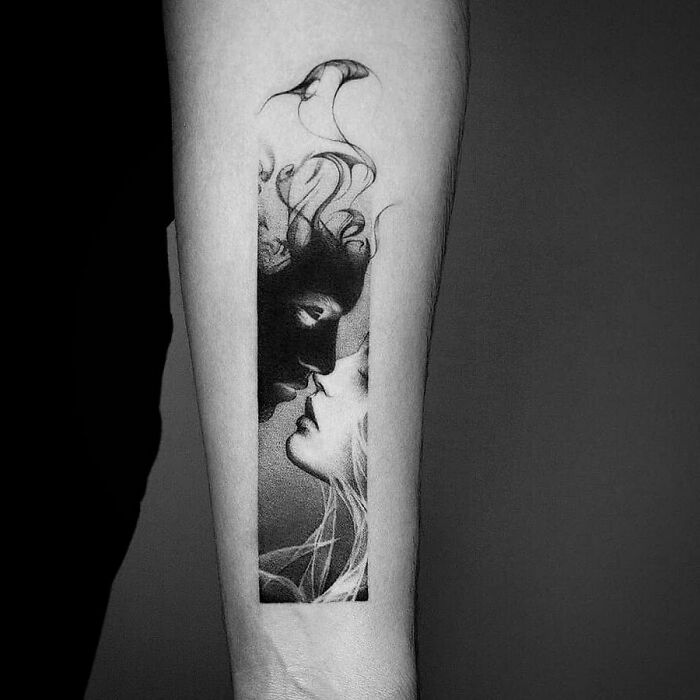 Unique tattoo design of two abstract faces in black and white on a forearm.