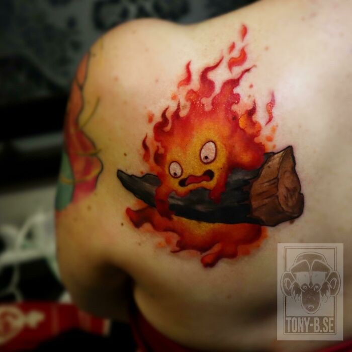 Creative tattoo design of a fiery creature holding a log on a person's shoulder.