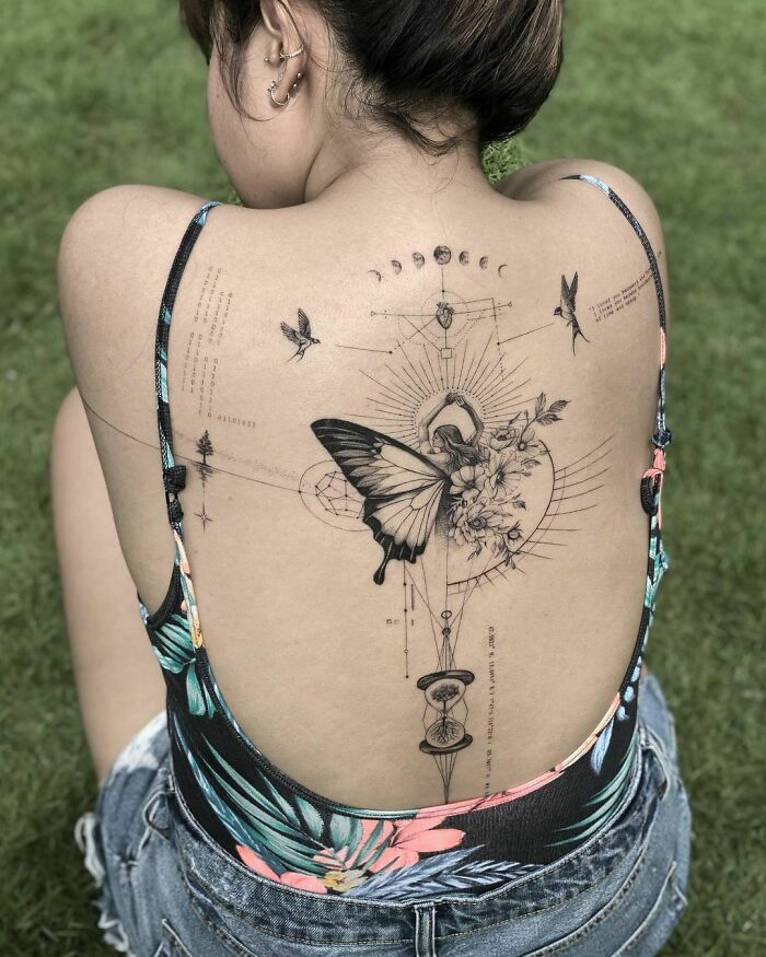 Intricate tattoo design featuring a butterfly and celestial motifs on a woman's back, showcasing creative tattoo art.