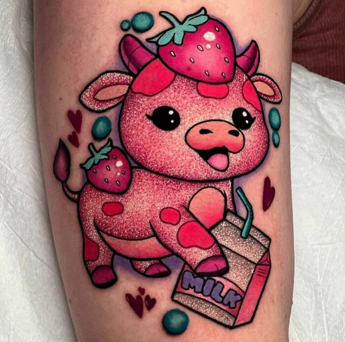 Cute glitter tattoo of a strawberry-themed cow holding a milk carton on the arm.