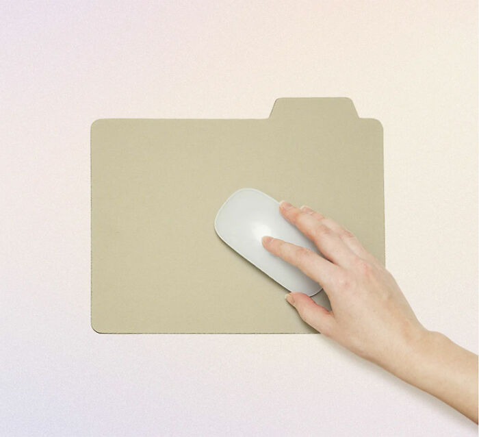 Hand using white computer mouse on a mouse pad shaped like a folder, reflecting unusual and conceptual product designs.