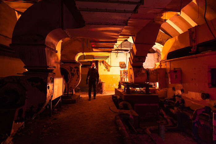 Person exploring abandoned industrial place at night illuminated using a lot of light for photography.