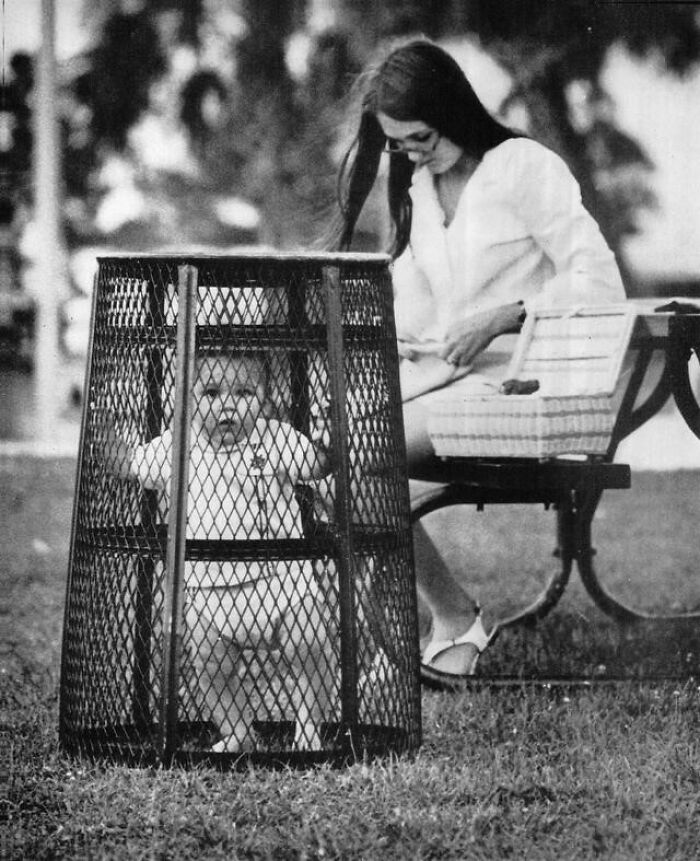 A Mother Uses A Trash Can To Contain Her Baby While She Crochets In The Park, 1969