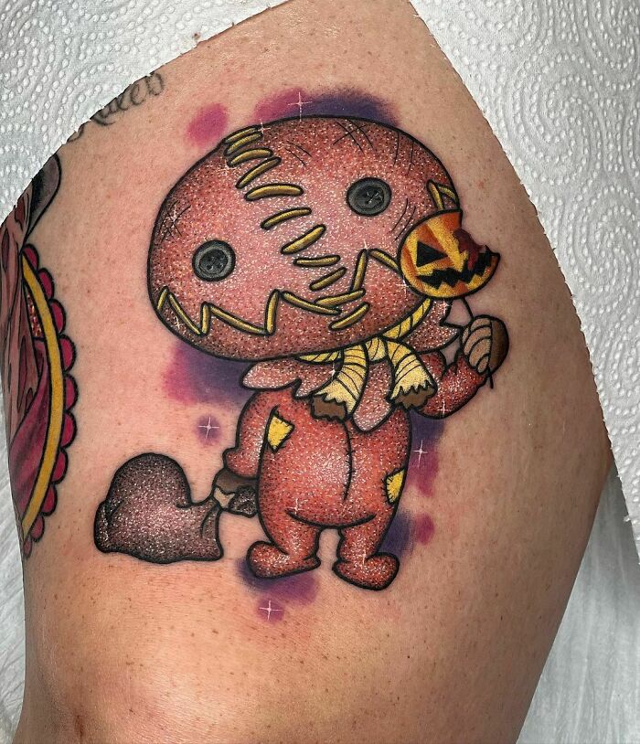 Cute pumpkin character glitter tattoo on skin.