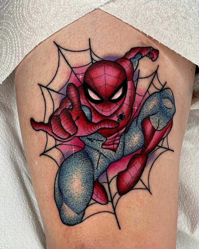 Glitter tattoo of a superhero in a dynamic pose with web design, showcasing shimmering effects and vibrant colors.