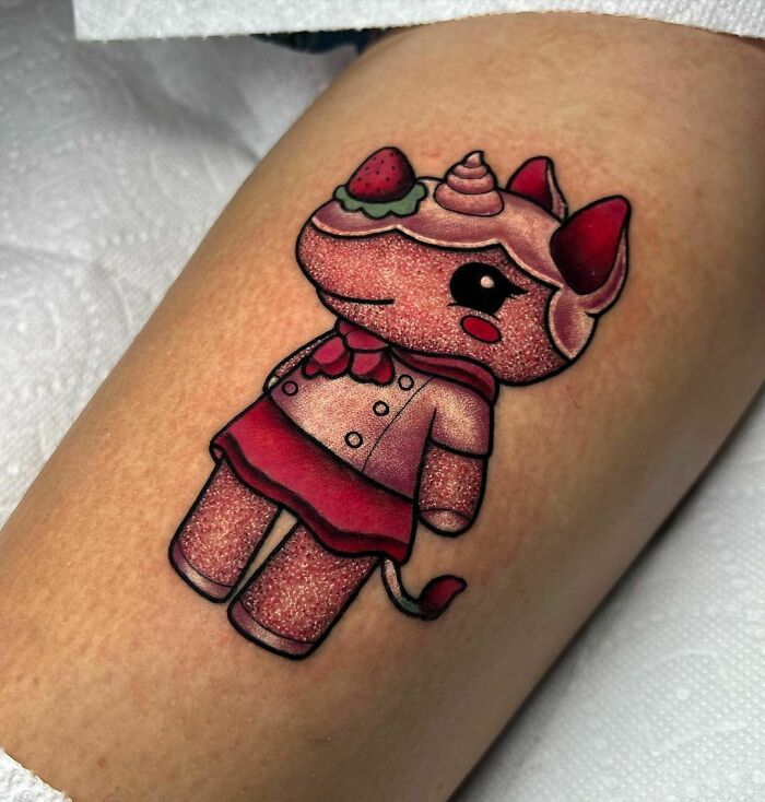Cute character glitter tattoo with strawberry and unicorn horn design on arm.