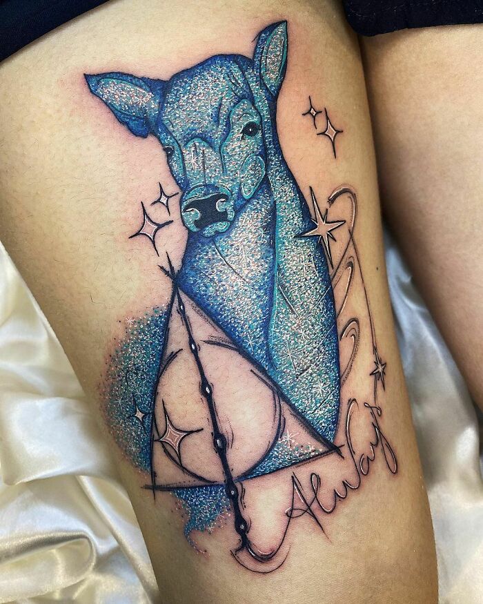 Cool glitter tattoo of a blue deer with stars and script on skin.