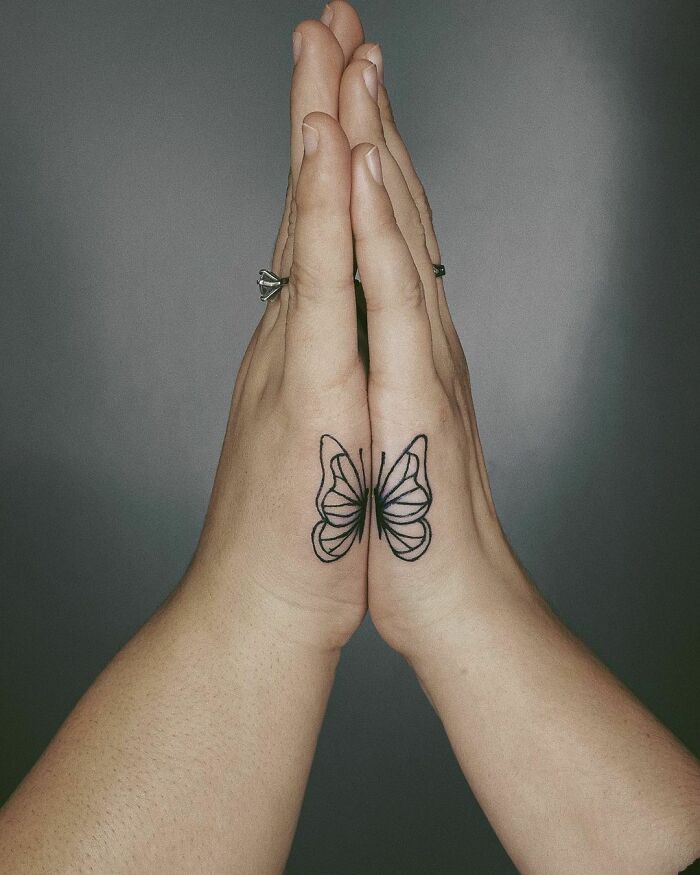 Butterfly tattoo on two hands touching, symbolizing best friend tattoos and the bond of friendship.