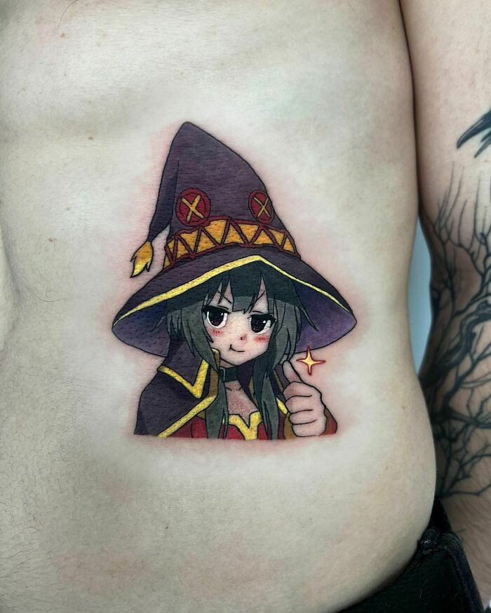Cartoon tattoo of a cute character with a witch hat on the side of a person's torso.