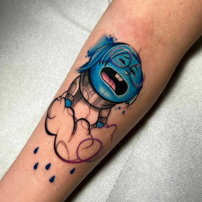 Sadness from Inside Out tattoo on arm, showcasing colorful cartoon nostalgia.