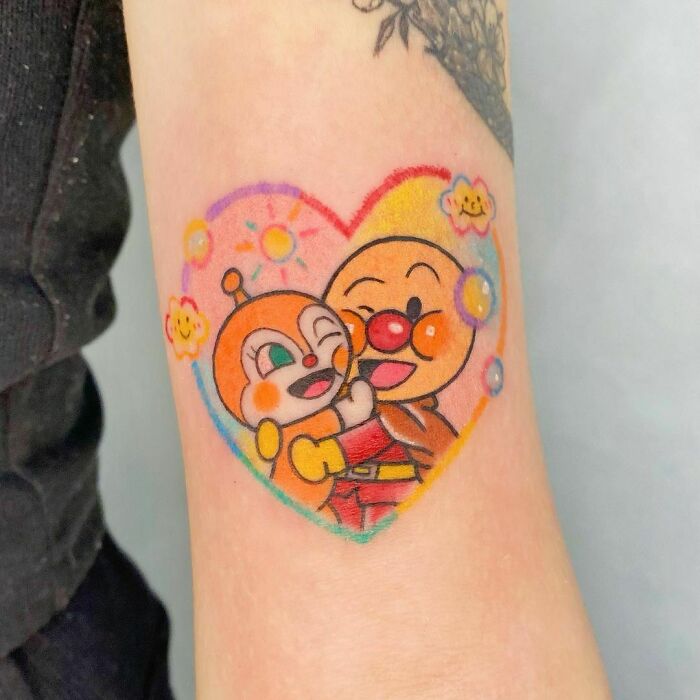 Cartoon tattoo featuring two colorful characters in a heart shape, evoking childhood favorites.