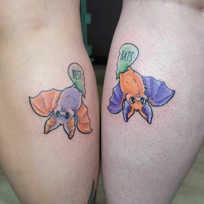 Colorful best friend tattoos of cartoon bats on two people.