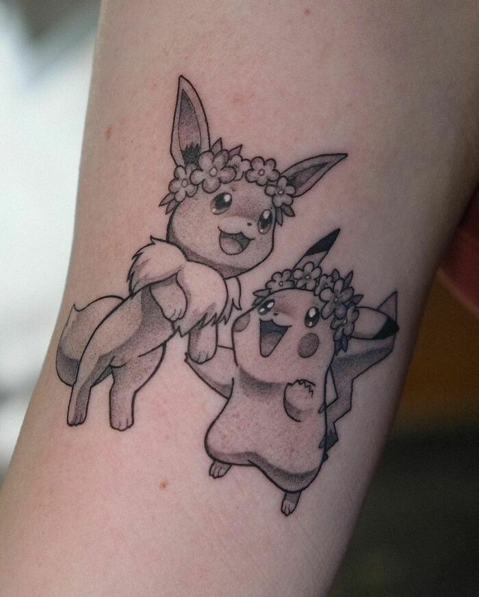 Cartoon tattoo of two lively characters with flower crowns on a forearm, inspired by popular animated shows.