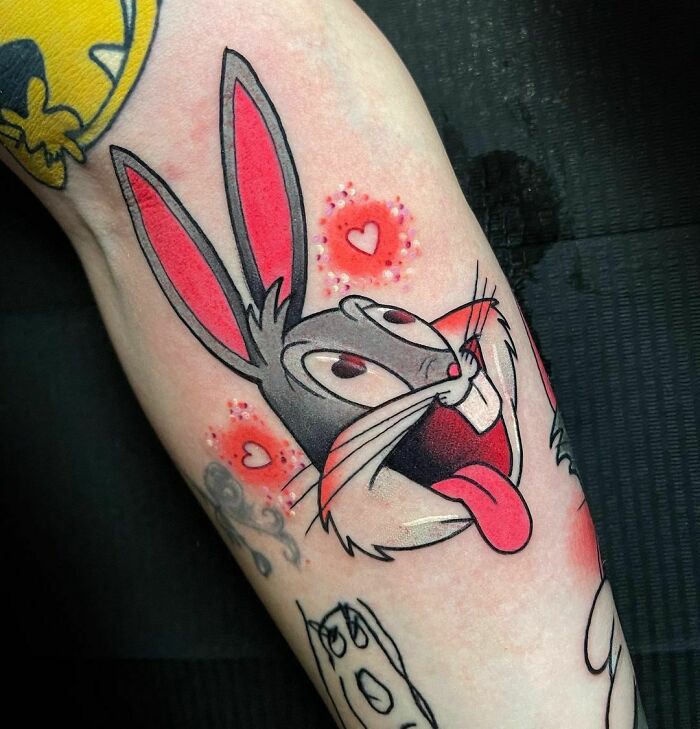 Cartoon tattoo of animated character with big ears and heart accents.