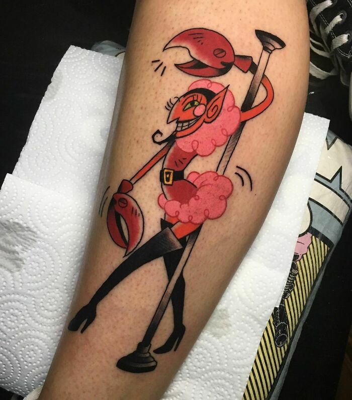Cartoon tattoo of a colorful creature with crab claws and high heels on a leg.