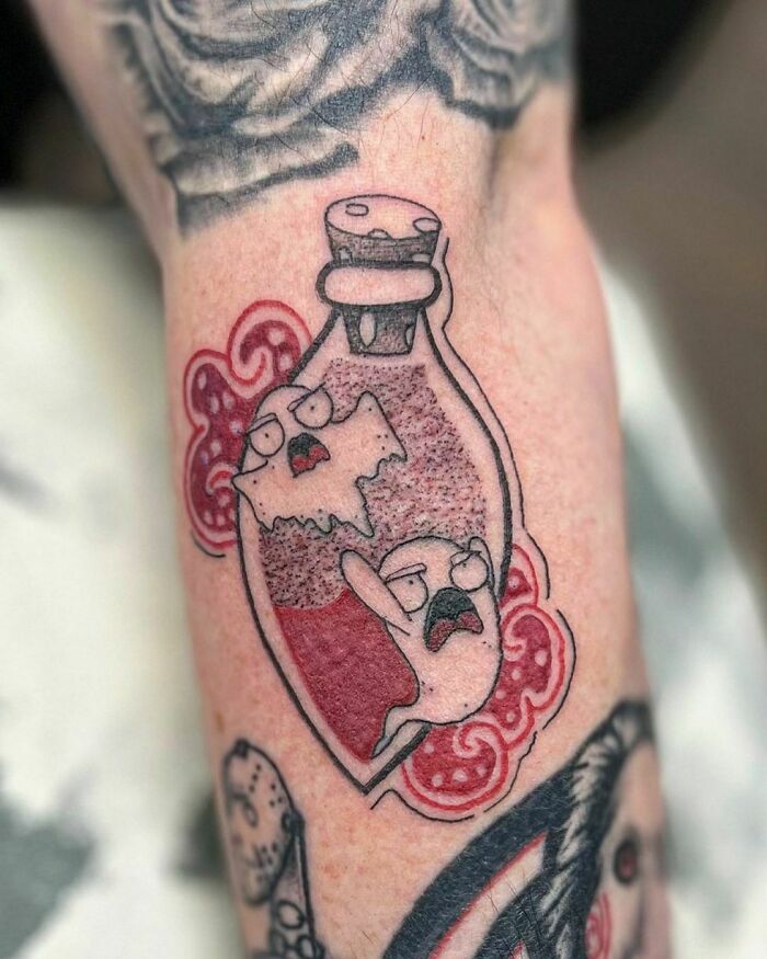 Cartoon tattoo of characters in a bottle, featuring bold lines and vibrant colors, inspired by childhood favorites.