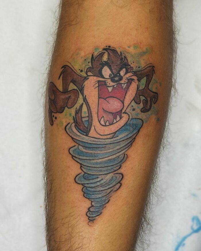 Cartoon tattoo of a wild, spinning Tasmanian Devil on a person's calf.