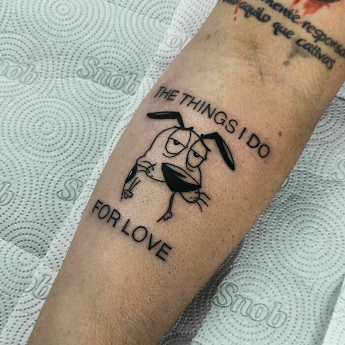 Cartoon tattoo of a dog with text "The Things I Do For Love" on an arm, echoing childhood favorites.