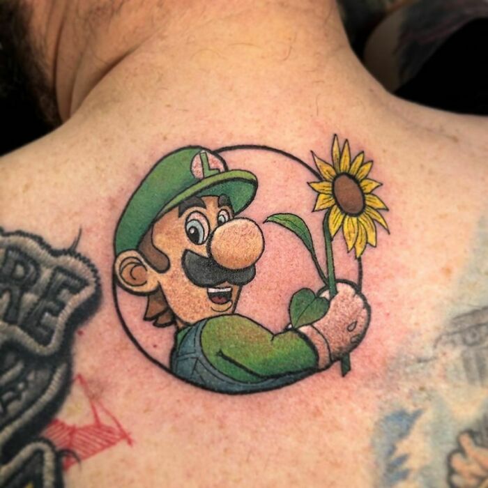Cartoon tattoo of a familiar character holding a sunflower on a person's shoulder.