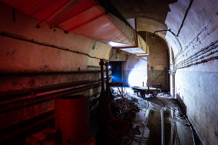 Abandoned place at night illuminated with bright lights showing old equipment and wet floor inside a tunnel.