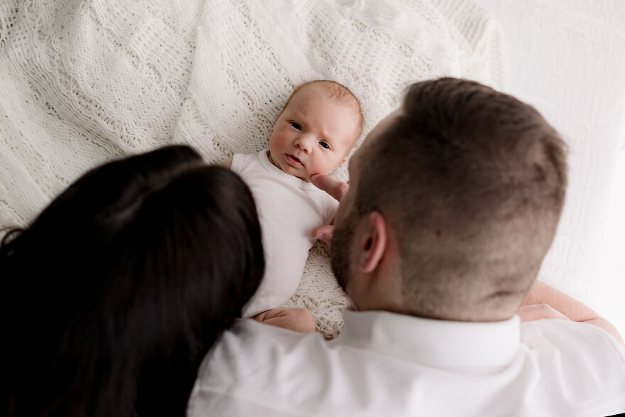 A photograph of a newborn with their parents