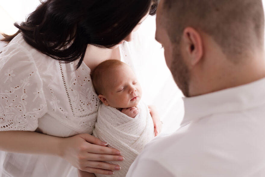 A photograph of a newborn with their parents