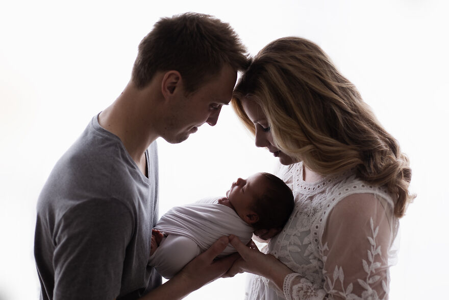A photograph of a newborn with their parents