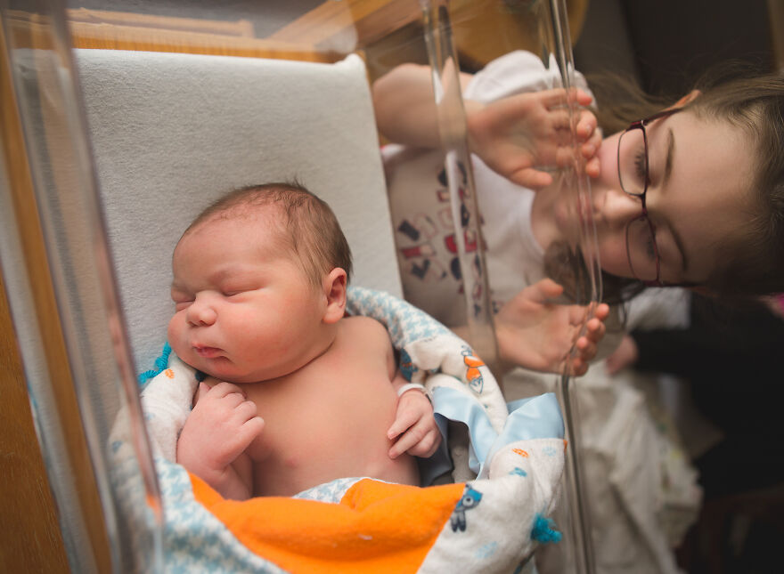 A photograph of a newborn with their sibling