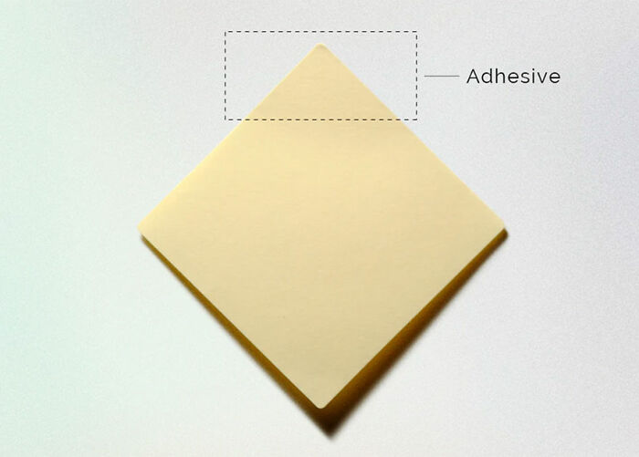 Unusual and conceptual product design showing adhesive area on a square sticky note pad placed on a white surface.