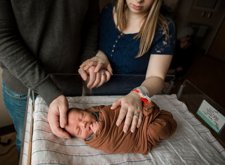 A photograph of a newborn with their parents