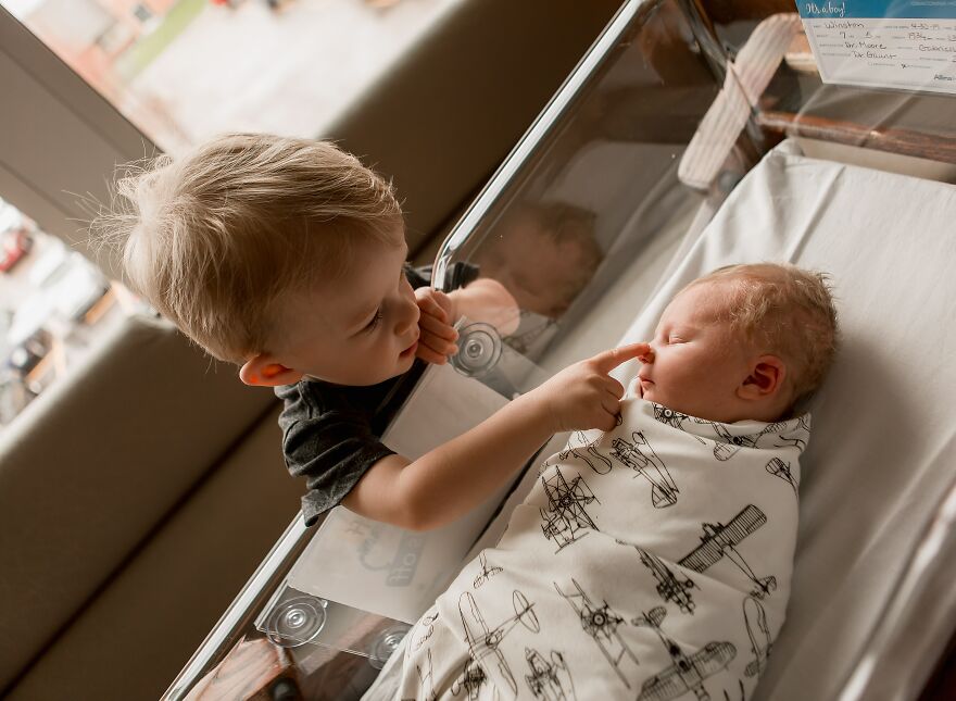 A photograph of a newborn with their sibling