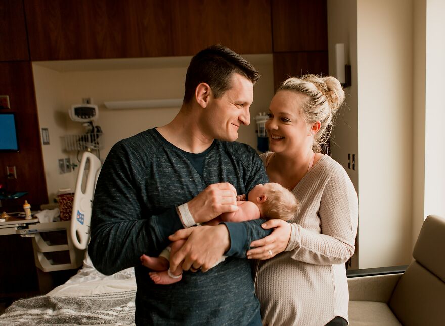 A photograph of a newborn with their parents