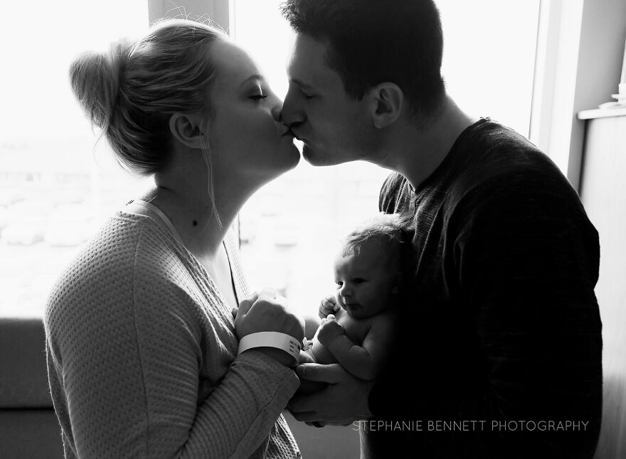 A photograph of a newborn with their parents