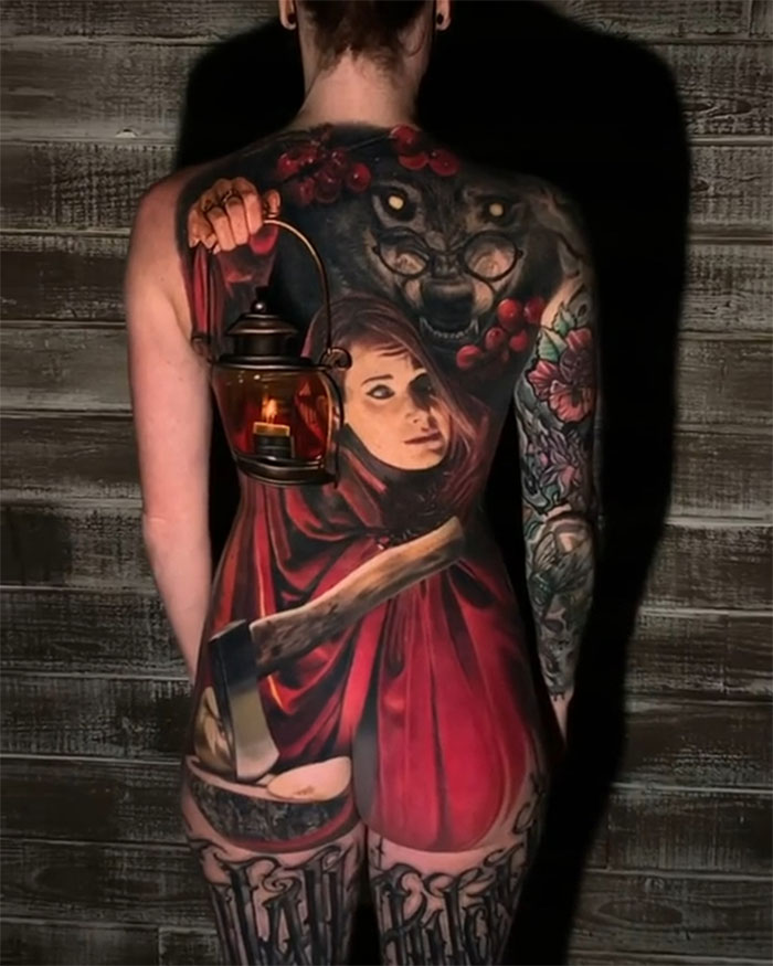 Creative tattoo design of Little Red Riding Hood and wolf on person's back.