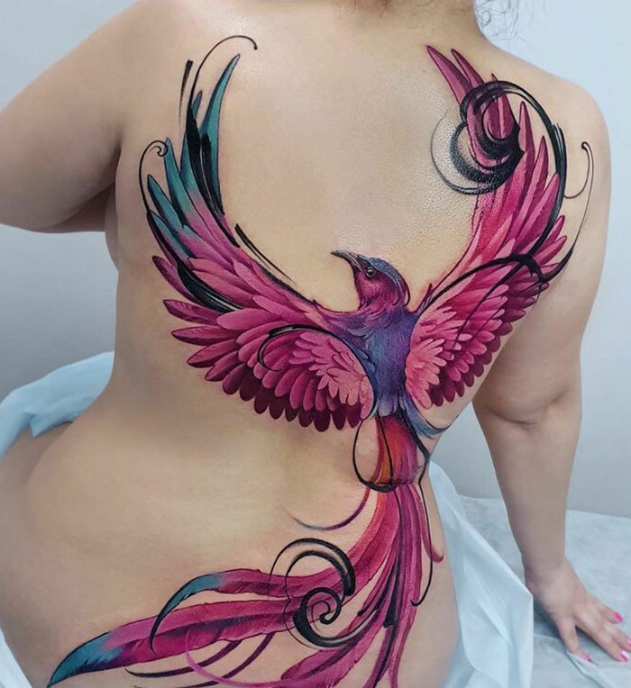 Colorful phoenix tattoo design on a person's back, showcasing intricate artistry and vibrant colors.